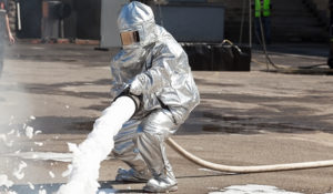 Pace Analytical the PFAS Pipeline. Airports & PFAS. Firefighter in protective suit spraying fire fighting foam.
