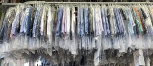 Dry Cleaners. Dry Cleaning items hanging up on rack covered in plastic.