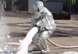 Pace Analytical the PFAS Pipeline. Airports & PFAS. Firefighter in protective suit spraying fire fighting foam.